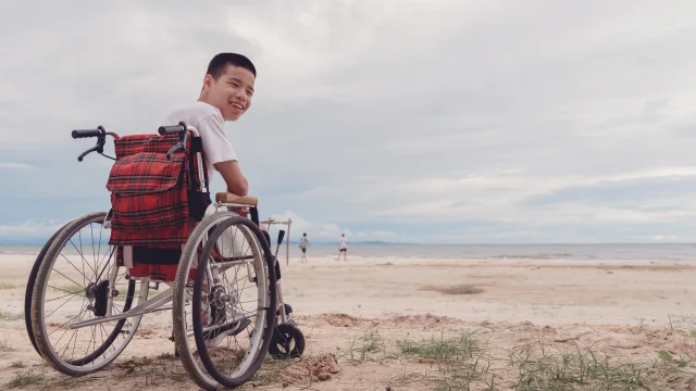 Young man with disability happy face, smiling on the beach,Outdoor vacation in summer,People leisure travel, mental health concept,Positive of lifestyle,International Day of Persons with Disabilities.