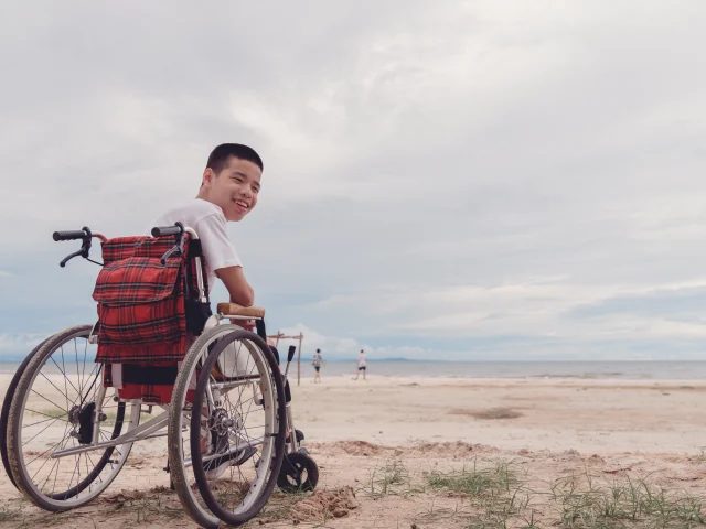 Young man with disability happy face, smiling on the beach,Outdoor vacation in summer,People leisure travel, mental health concept,Positive of lifestyle,International Day of Persons with Disabilities.