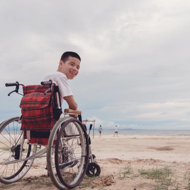 Young man with disability happy face, smiling on the beach,Outdoor vacation in summer,People leisure travel, mental health concept,Positive of lifestyle,International Day of Persons with Disabilities.